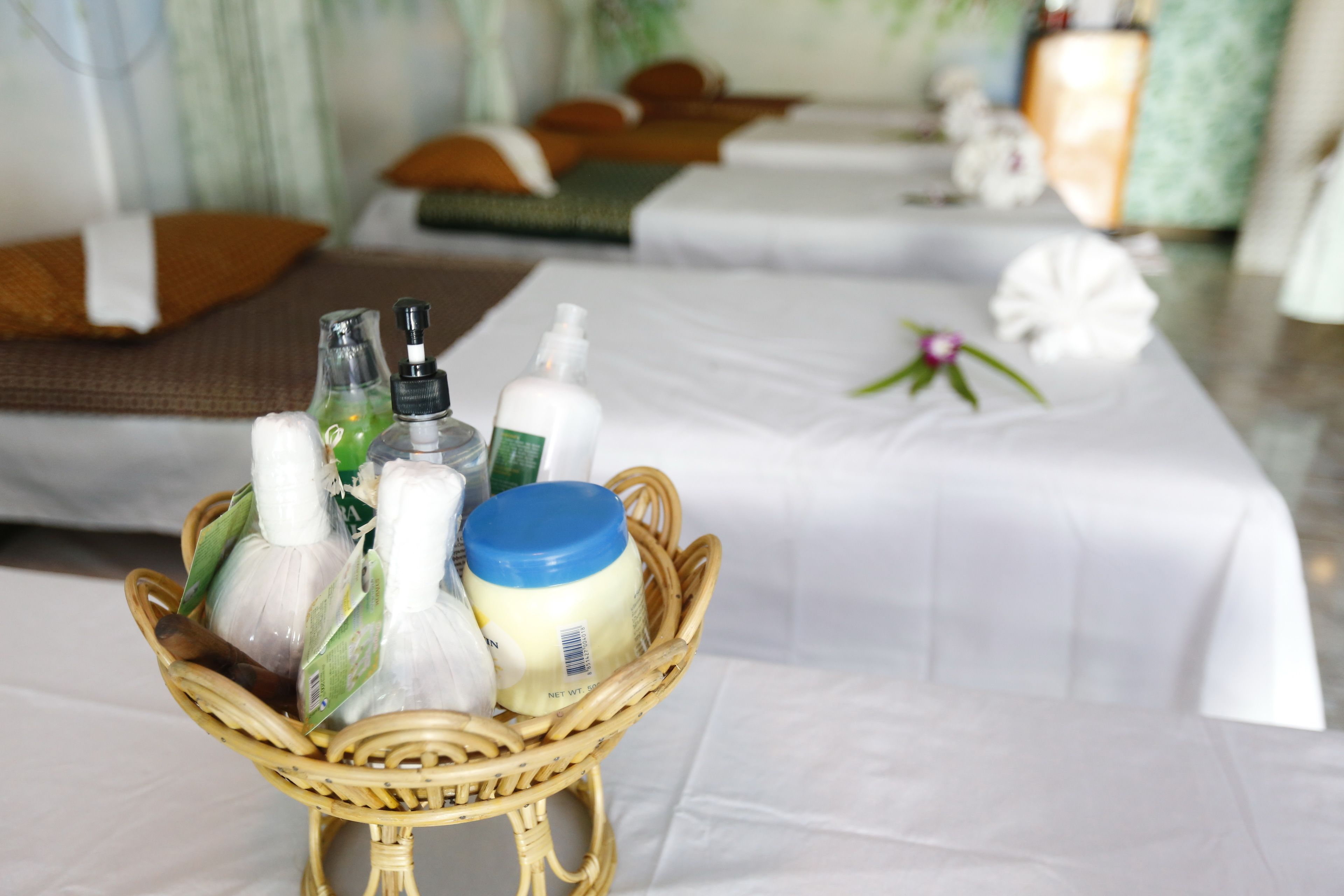 A room with a bed, a small wicker basket with toiletries, and a white tablecloth.