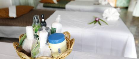 A room with a bed, a small wicker basket with toiletries, and a white tablecloth.