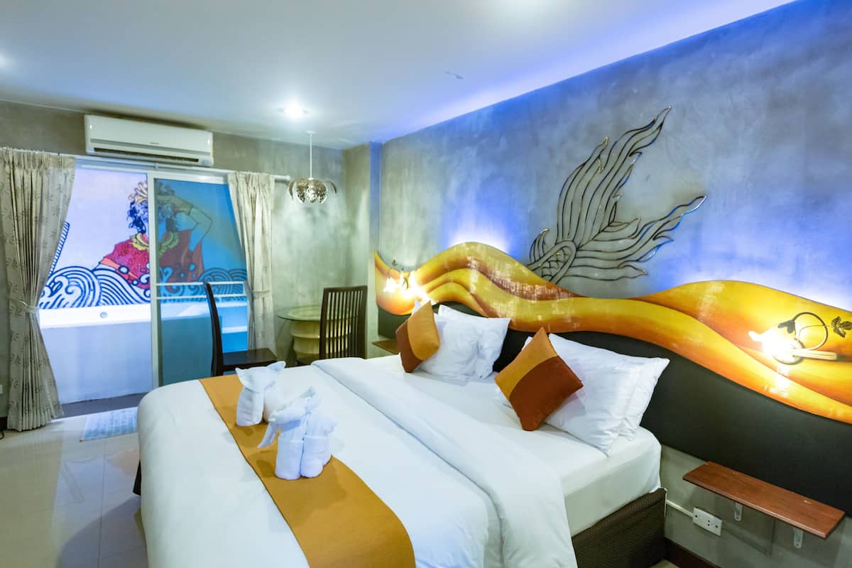 Ein Hotelzimmer mit einem großen Bett, einem Gemälde an der Wand und einem Fenster mit Vorhängen.