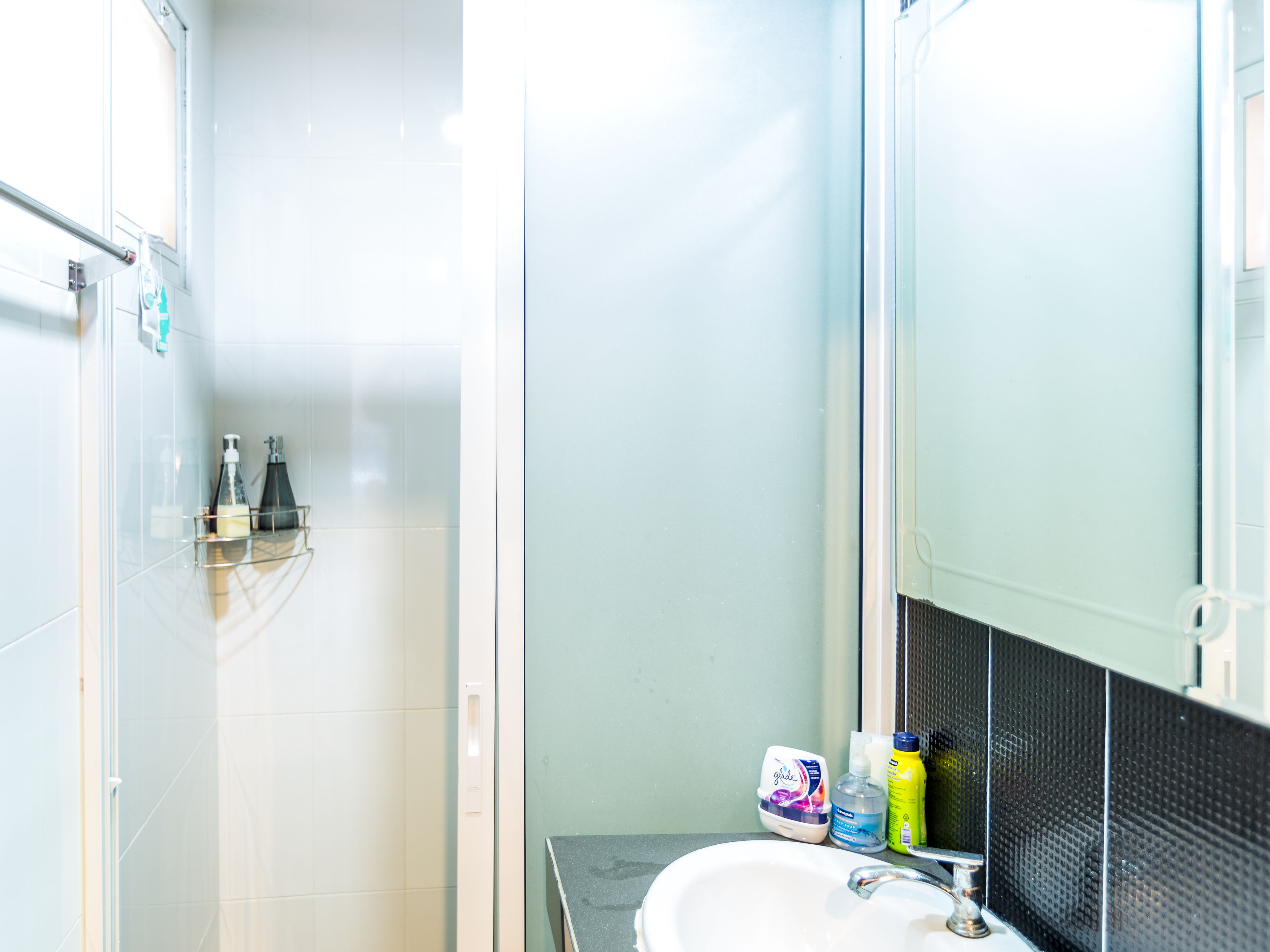 A bathroom with a white sink, a mirror, and toiletries on the counter.