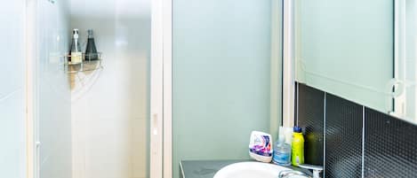 A bathroom with a white sink, a mirror, and toiletries on the counter.