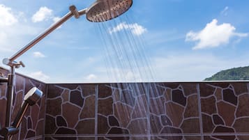 Un cabezal de ducha con agua corriendo por una pared de piedra.