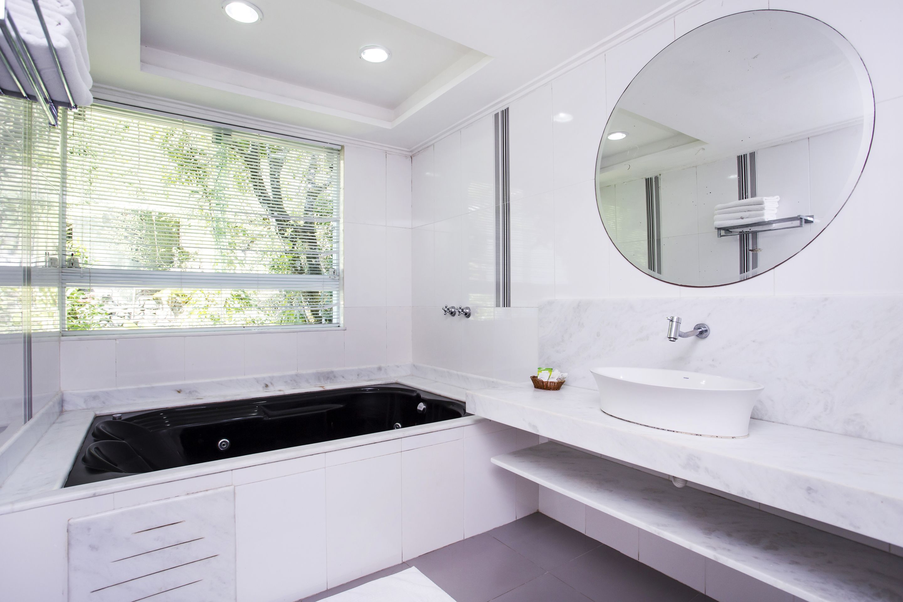 A modern bathroom with a black bathtub, a white sink, and a large mirror.