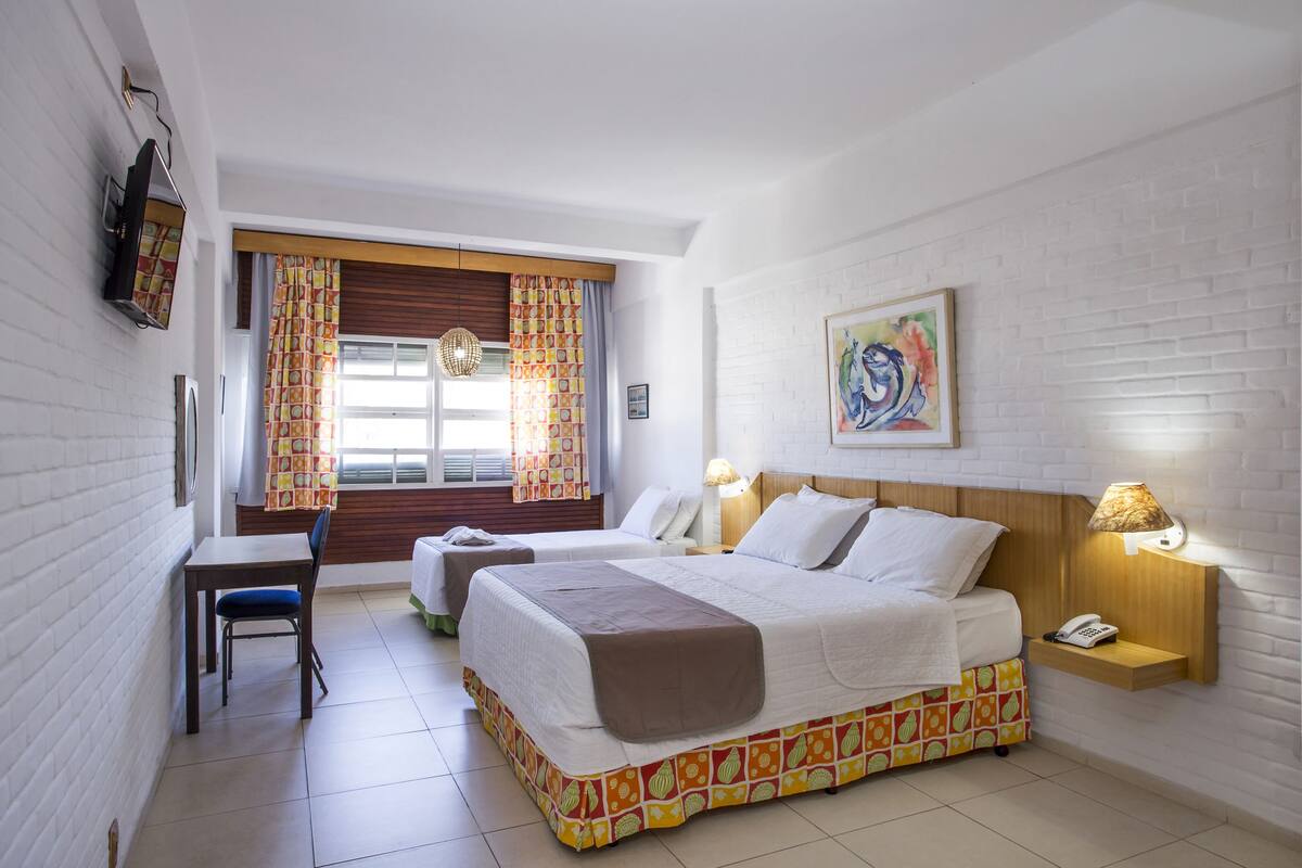 Una habitación de hotel con una cama, mesitas de noche, un escritorio y una silla.