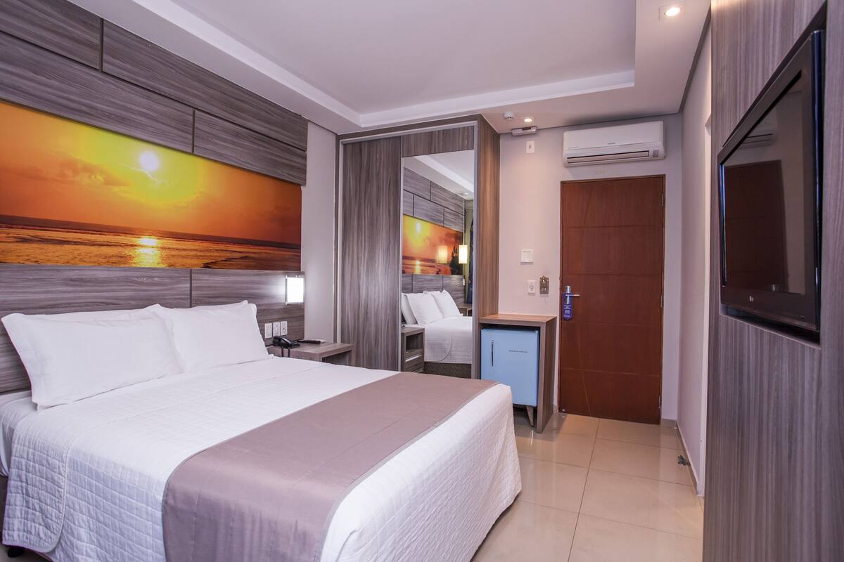 Una habitación de hotel moderna con una cama grande, un escritorio, un espejo y un televisor.
