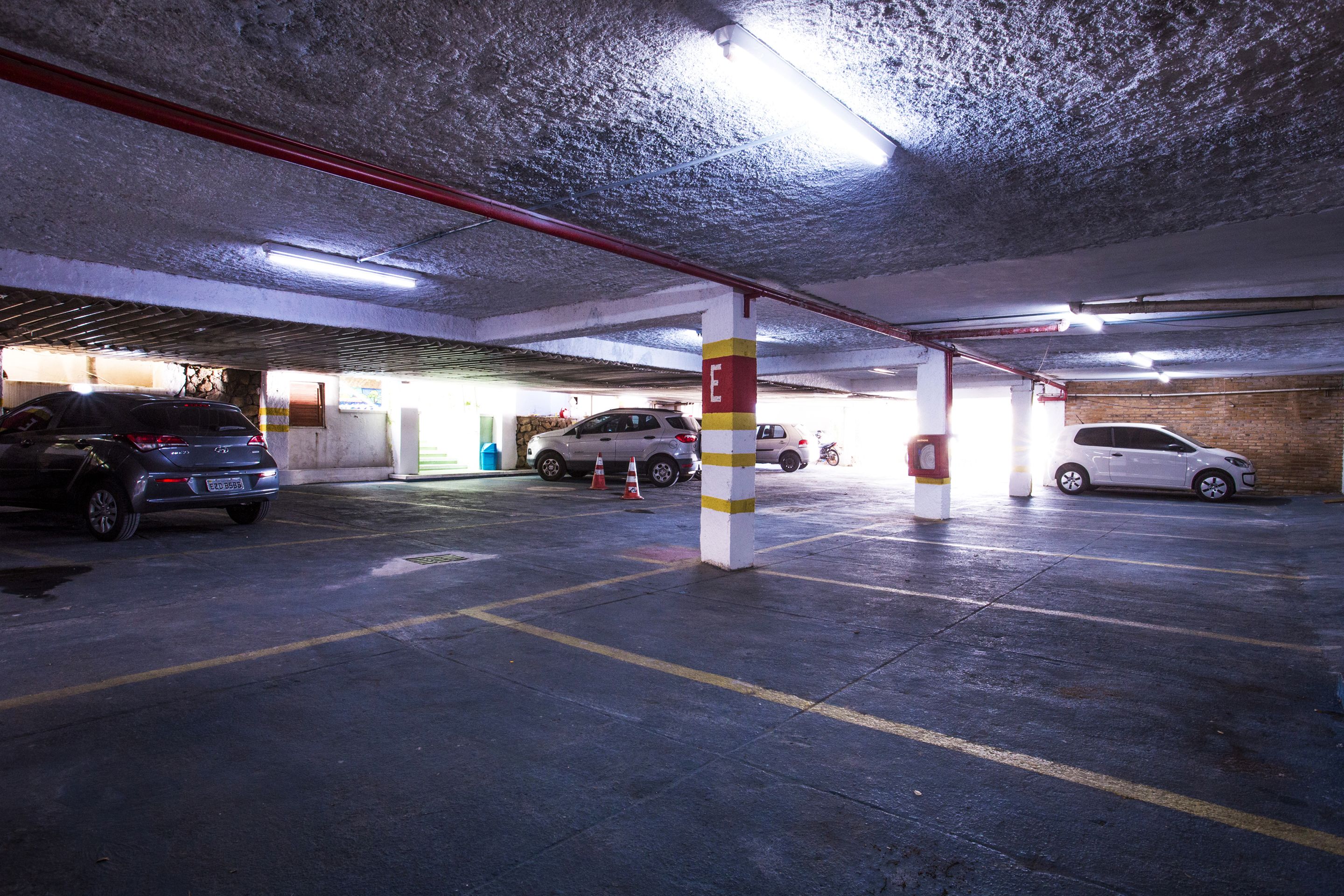 Un parking souterrain à plusieurs niveaux, avec des piliers en béton, un éclairage fluorescent et plusieurs voitures garées.