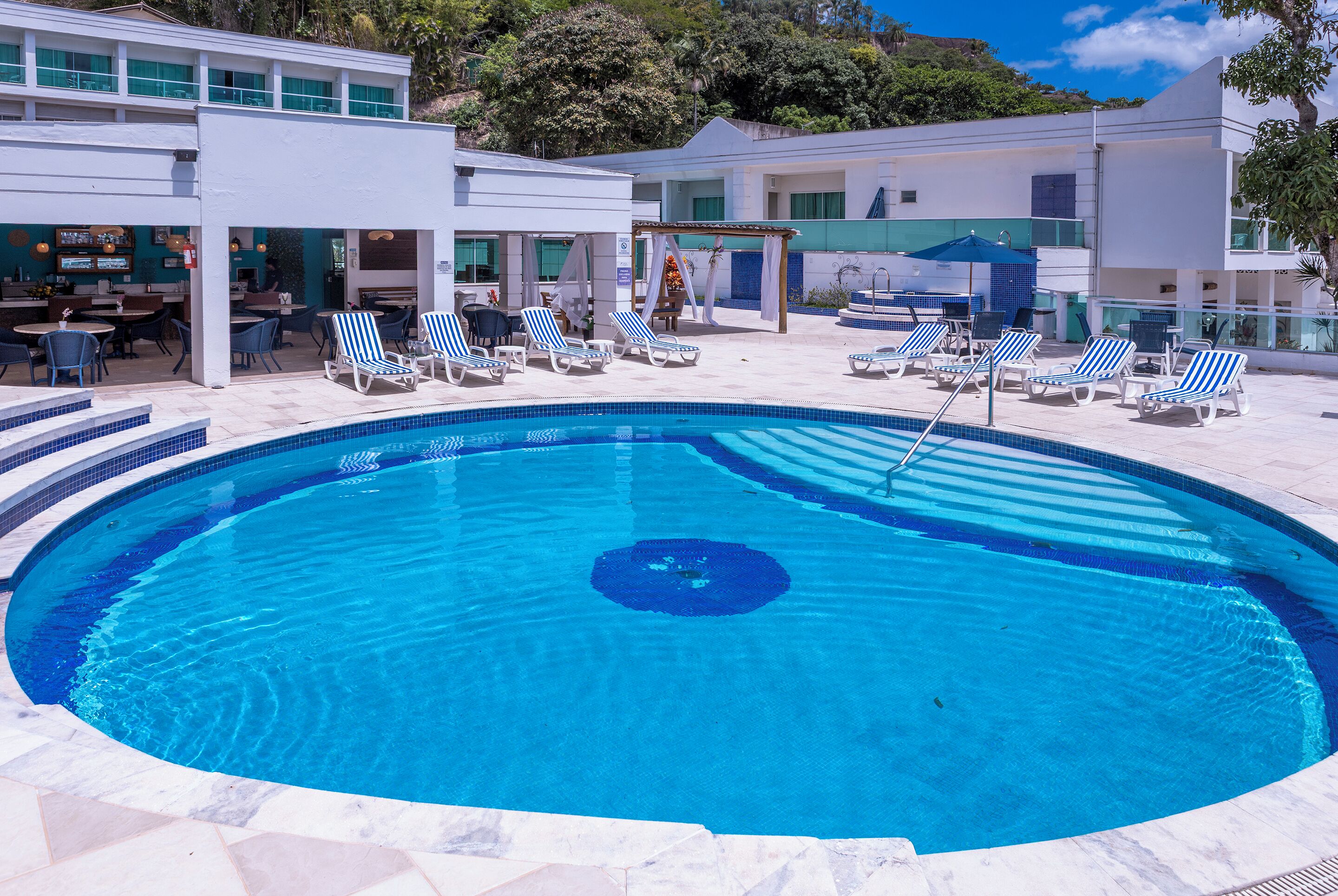 A pool area with lounge chairs and a bar.