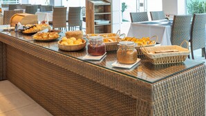 Een buffetopstelling met diverse gerechten en containers, rieten meubilair en een modern interieur.