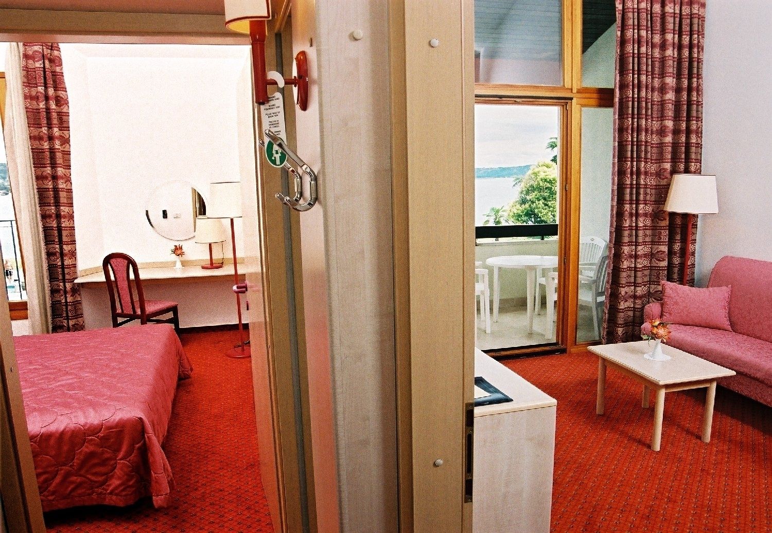 Habitación de hotel con cama, escritorio, silla, sofá, mesita y balcón con vistas.