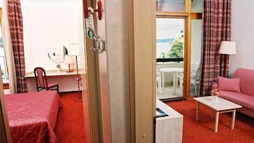 Habitación de hotel con cama, escritorio, silla, sofá, mesita y balcón con vistas.