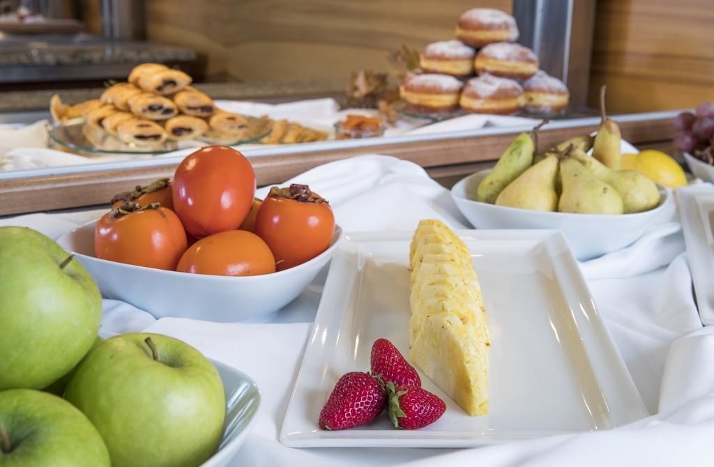 Ein Buffet mit verschiedenen Früchten, Gebäck und einer Portion Rührei.