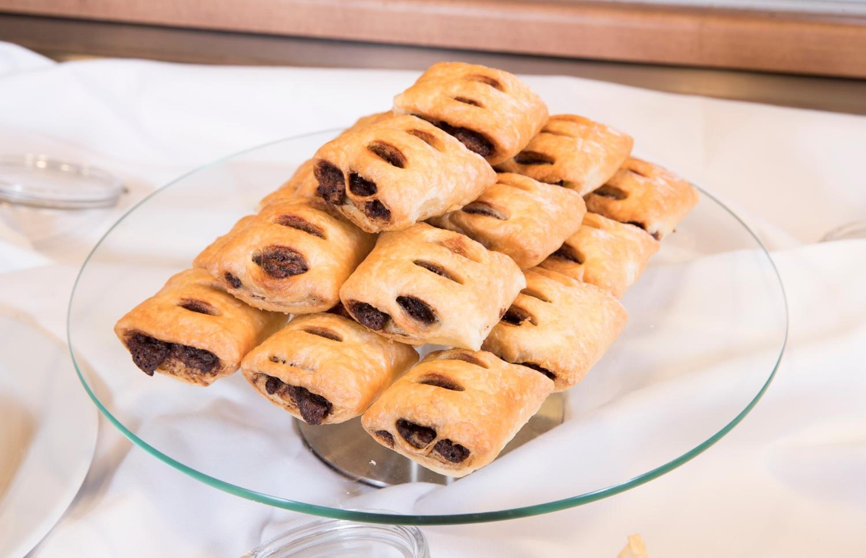 A glass plate with several golden-brown pastries on a white cloth.