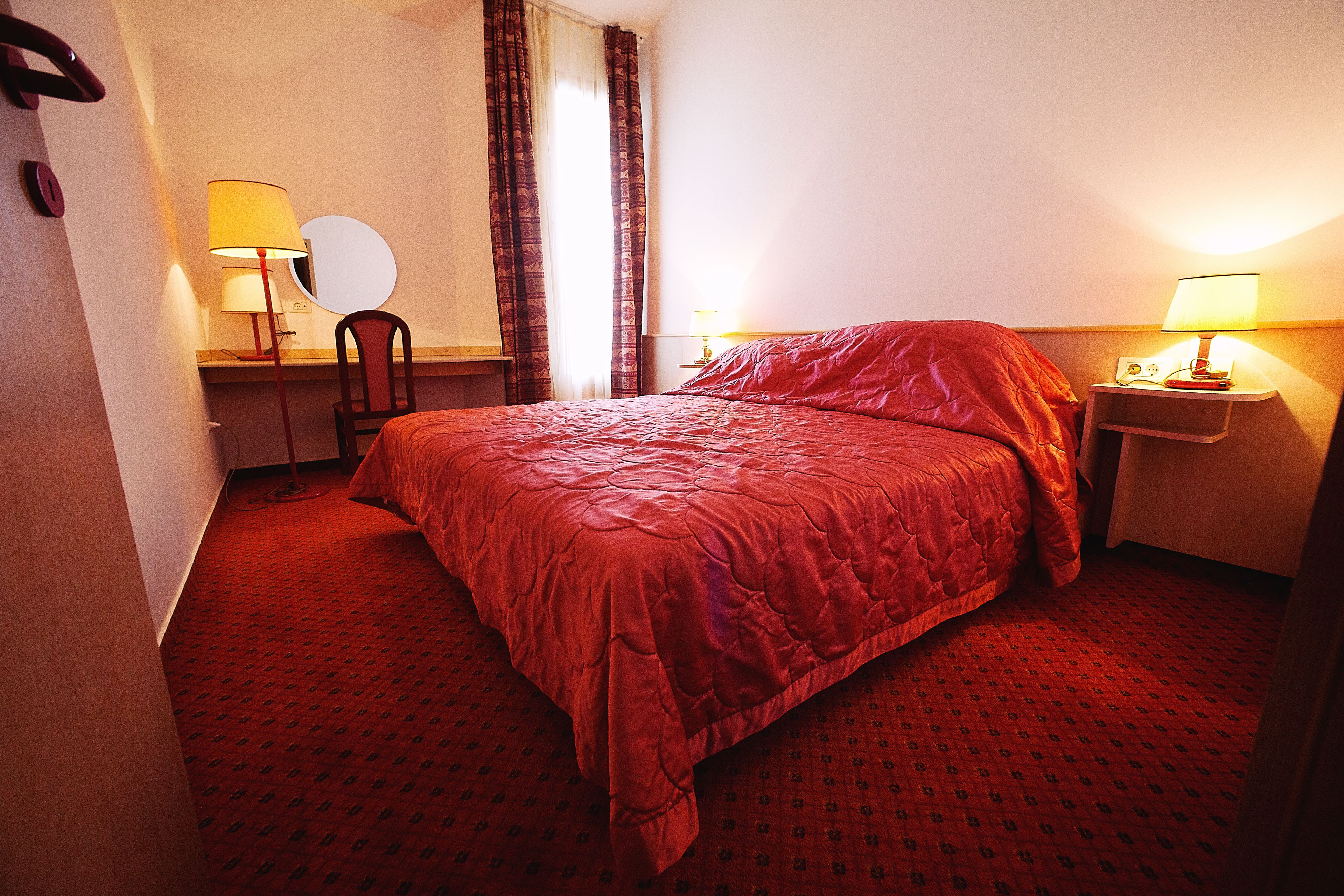 A hotel room with a large bed, two bedside tables with lamps, a chair, and a mirror.