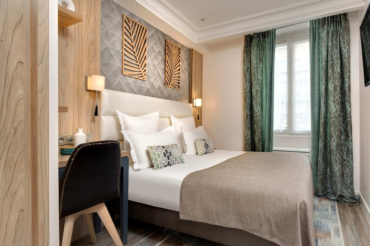Une chambre d’hôtel comprenant un lit, des tables de chevet, un bureau et une chaise.