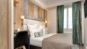 A hotel room with a bed, bedside tables, a desk, and a chair. - Serotel Suites (Paris)