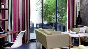 A modern living room with a sofa set, a dining table, and a laptop on a desk. - Serotel Suites (Paris)