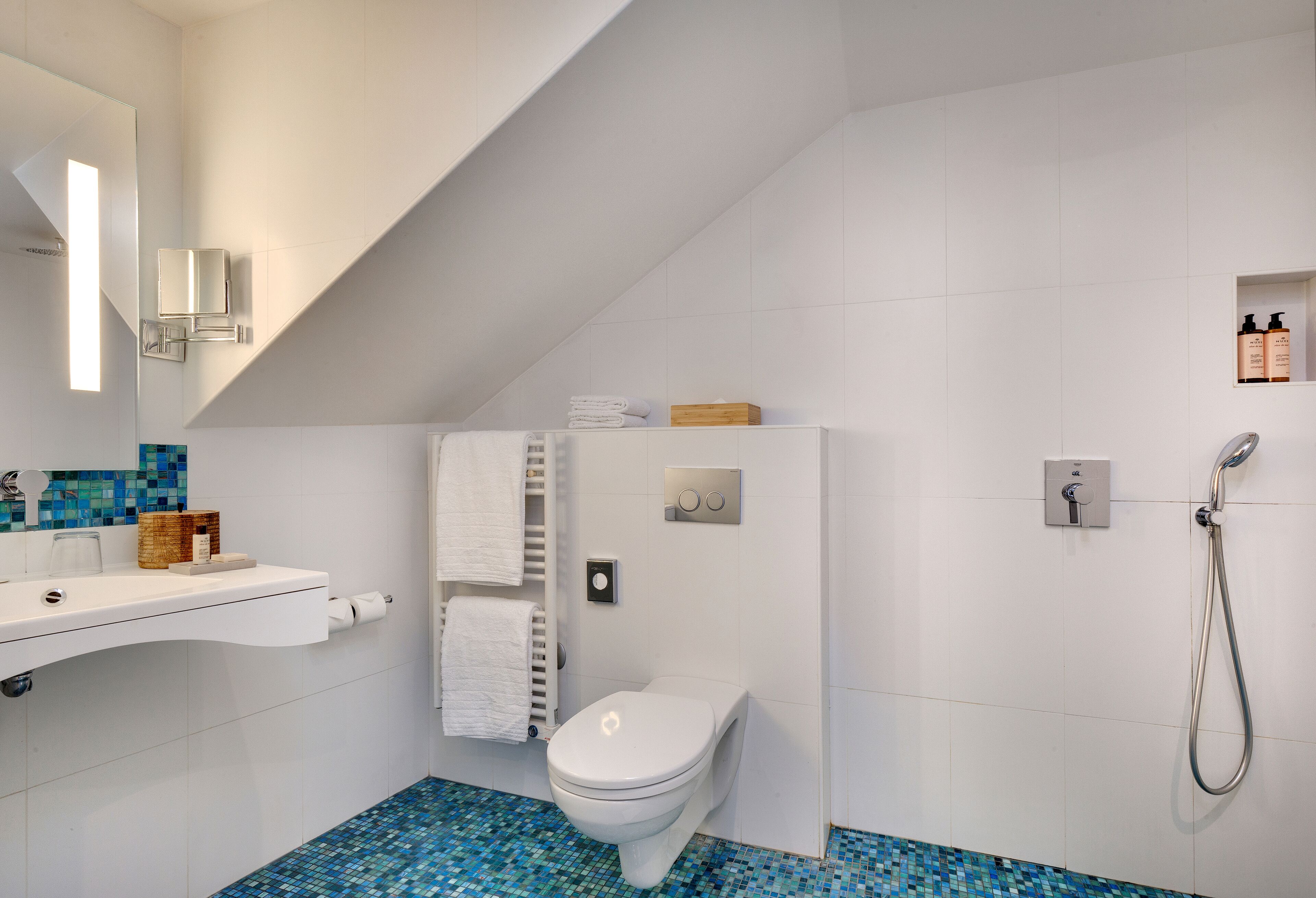 A modern bathroom with a white toilet, a shower, and a sink with a mirror.