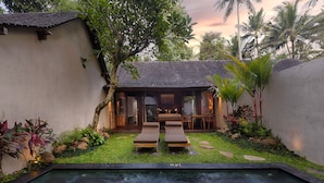 A pool area with two lounge chairs, a small covered seating area, and a garden with tropical plants. - Ubud Padi Villas (Ubud)