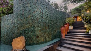 A stone wall with a carved inscription, a set of steps leading to a building, and several large terracotta pots. - Ubud Padi Villas (Ubud)