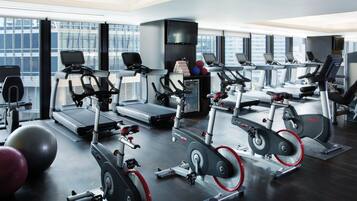 Un gimnasio moderno con varias máquinas de cardio, incluidas cintas de correr y bicicletas estáticas, y pelotas de ejercicio.
