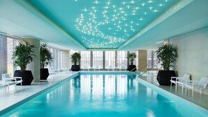 A swimming pool with a ceiling of lights, large windows, and potted plants. - The Langham, Chicago (Chicago)