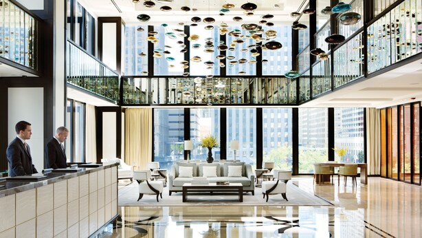 A modern hotel lobby with a reception desk, seating area, and large windows offering city views. - The Langham, Chicago (Chicago)