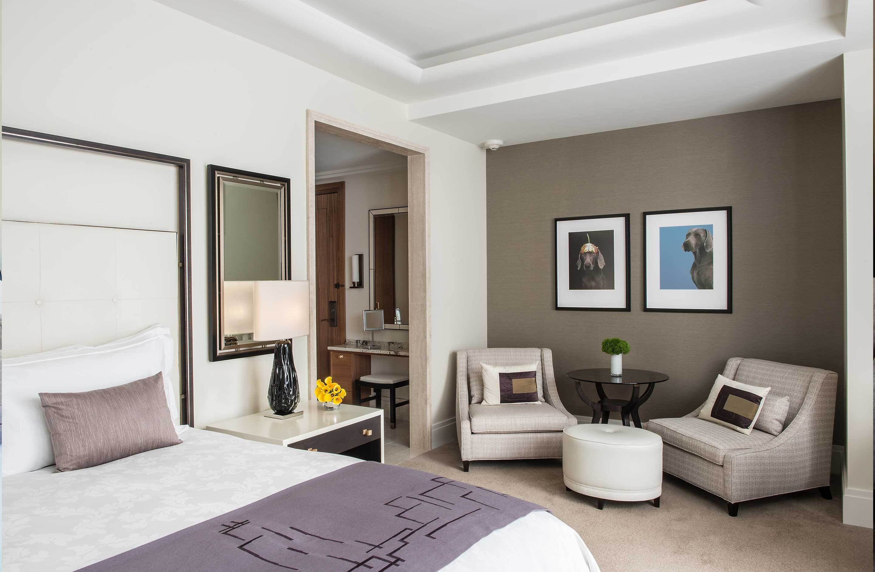 Habitación de hotel con cama, escritorio, silla, sofá, una mesita y un espejo.