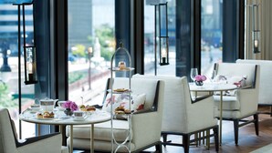 A modern dining area with round tables, comfortable chairs, and a dessert display. - The Langham, Chicago (Chicago)