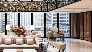 A spacious lobby with a modern sofa, armchairs, and a coffee table. A large window offers a view of the cityscape. - The Langham, Chicago (Chicago)