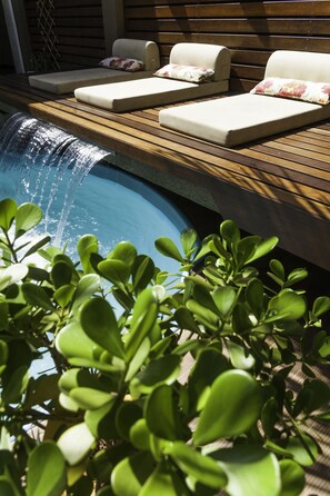 A poolside area with lounge chairs and a small waterfall feature. - Hotel Holiday Foz (Foz do Iguaçu)