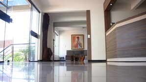 Un vestíbulo amplio con piso pulido, un ventanal grande y un cuadro en la pared.