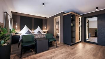 A modern bedroom with a bed, two chairs, a desk, and a wardrobe.