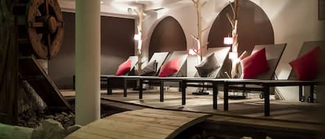 Un área de spa con camillas de masaje, decoración de madera y pared de piedra.