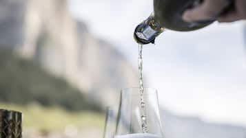 Un verre se remplit d’un liquide transparent à l’extérieur, avec un paysage montagneux en arrière-plan.