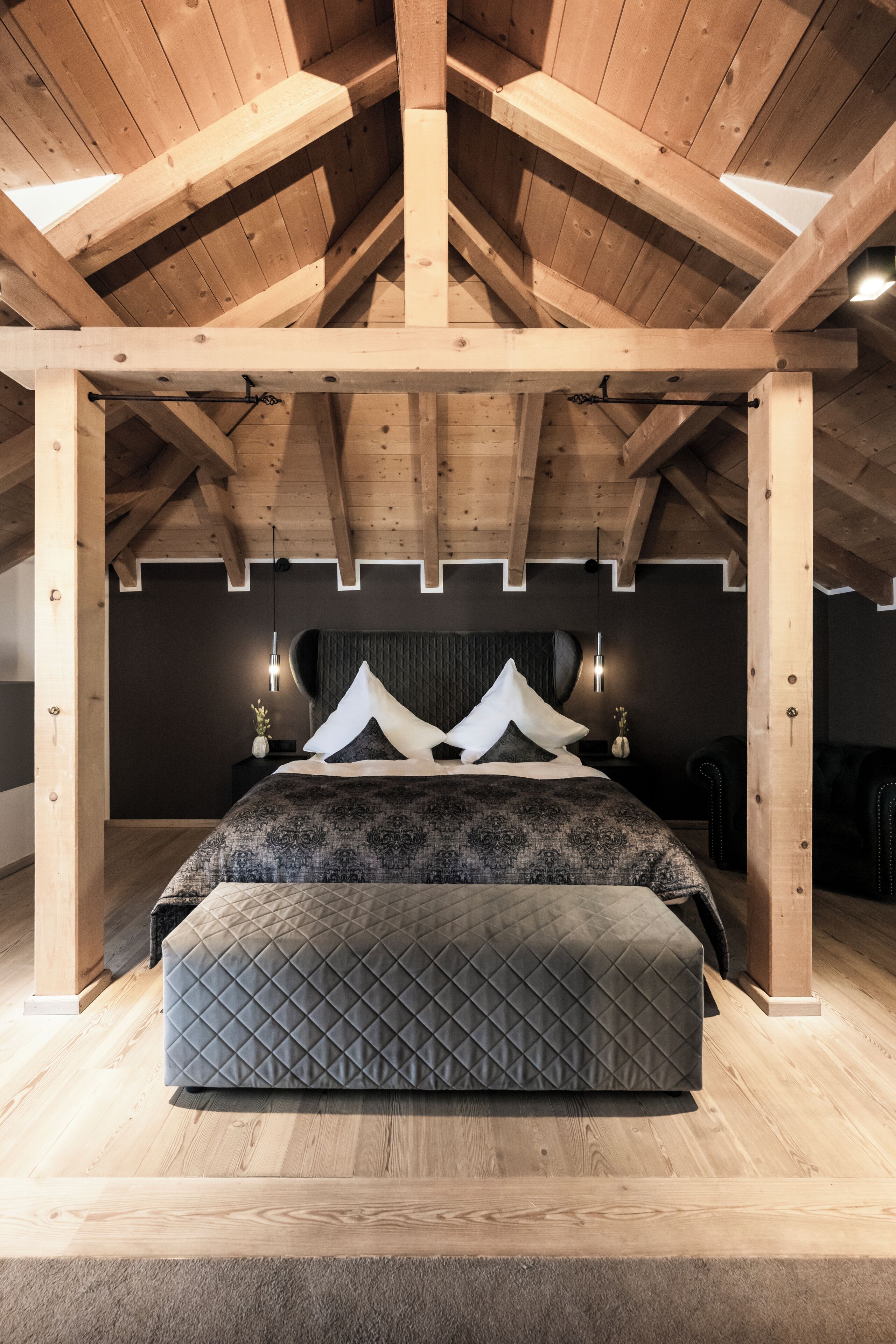 Um quarto com teto de madeira, uma cama com colchão acolchoado e duas luminárias de cabeceira.