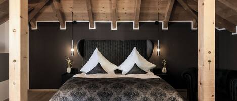 A bedroom with a wooden ceiling, a bed with a quilted mattress, and two bedside lamps.