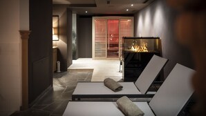 A modern lounge area with two reclining chairs, a fireplace, and a stone-tiled floor.