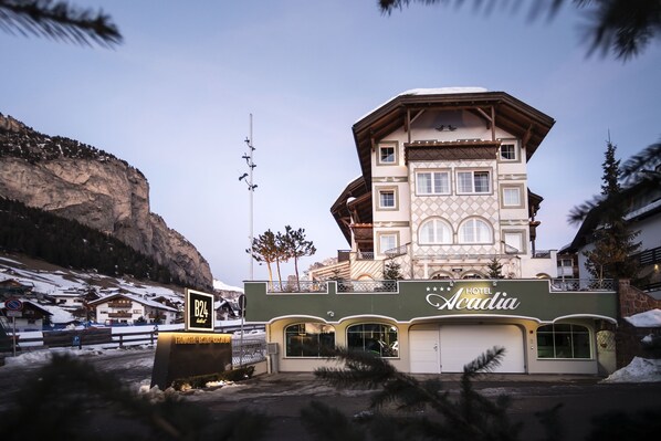 Un hotel con un letrero llamativo, un balcón y montañas al fondo.