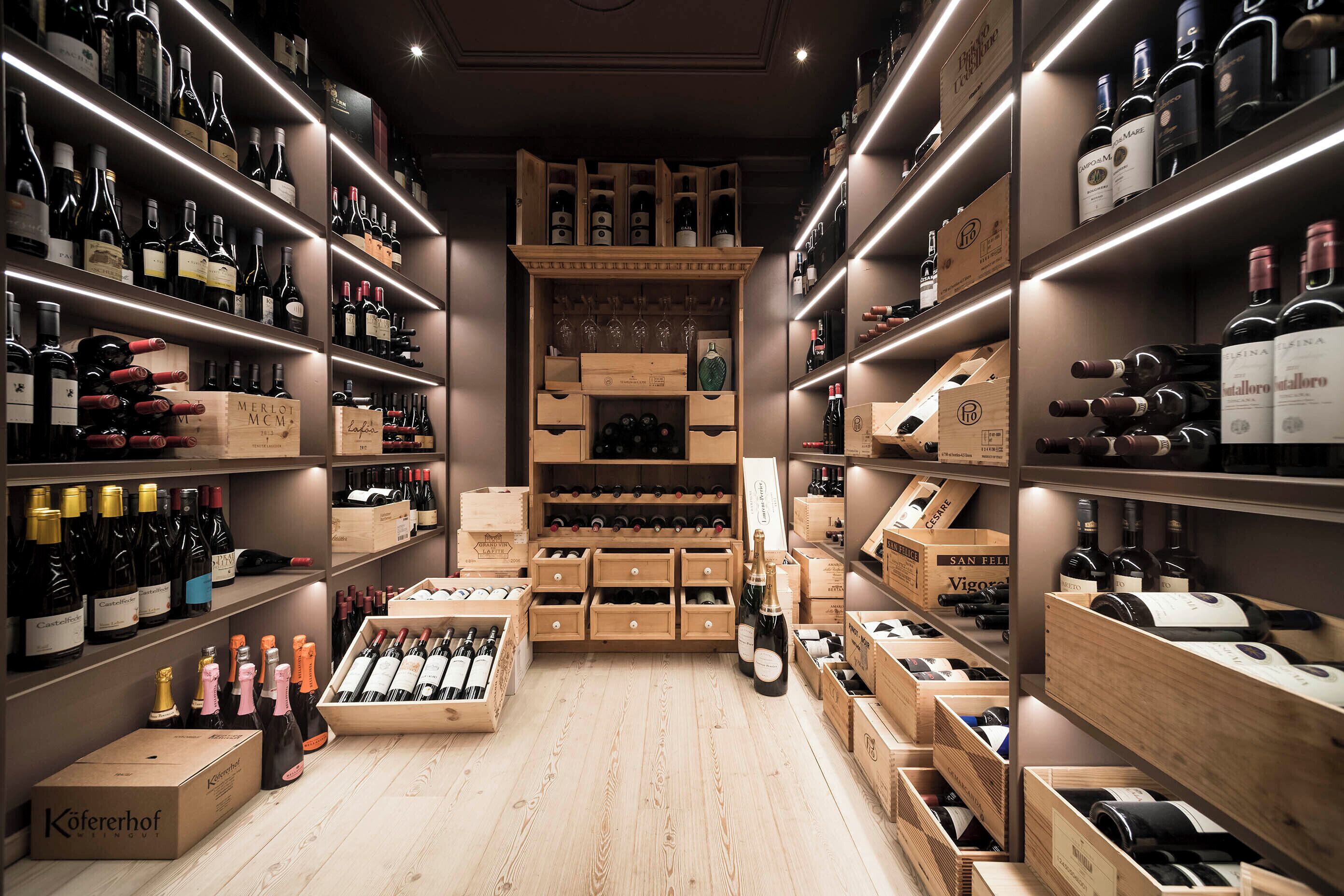 Une cave à vin avec des étagères et des caisses en bois contenant différentes bouteilles.