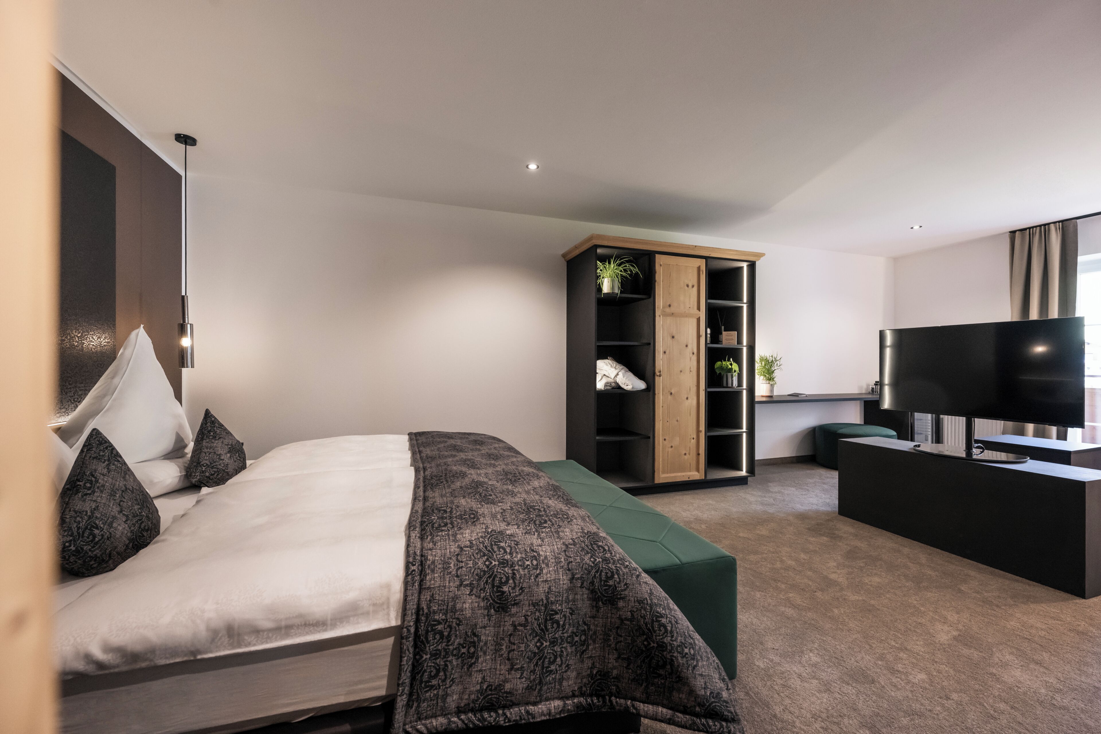 Un dormitorio moderno con cama, armario, televisor y escritorio.