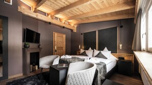 Un dormitorio moderno con cama, mesitas de noche, televisor y chimenea.