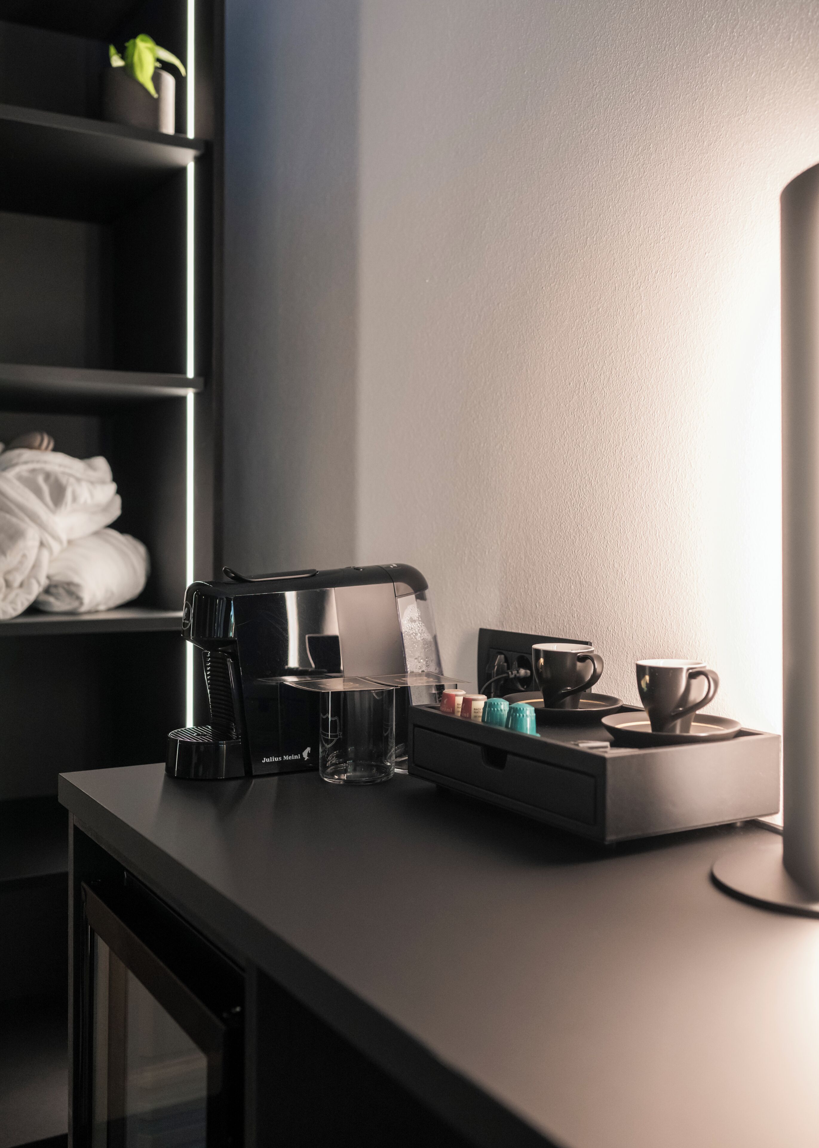 Eine moderne Küche mit Kaffeemaschine, einem Glas und einer Serviertablett mit Tassen und Gewürzen.