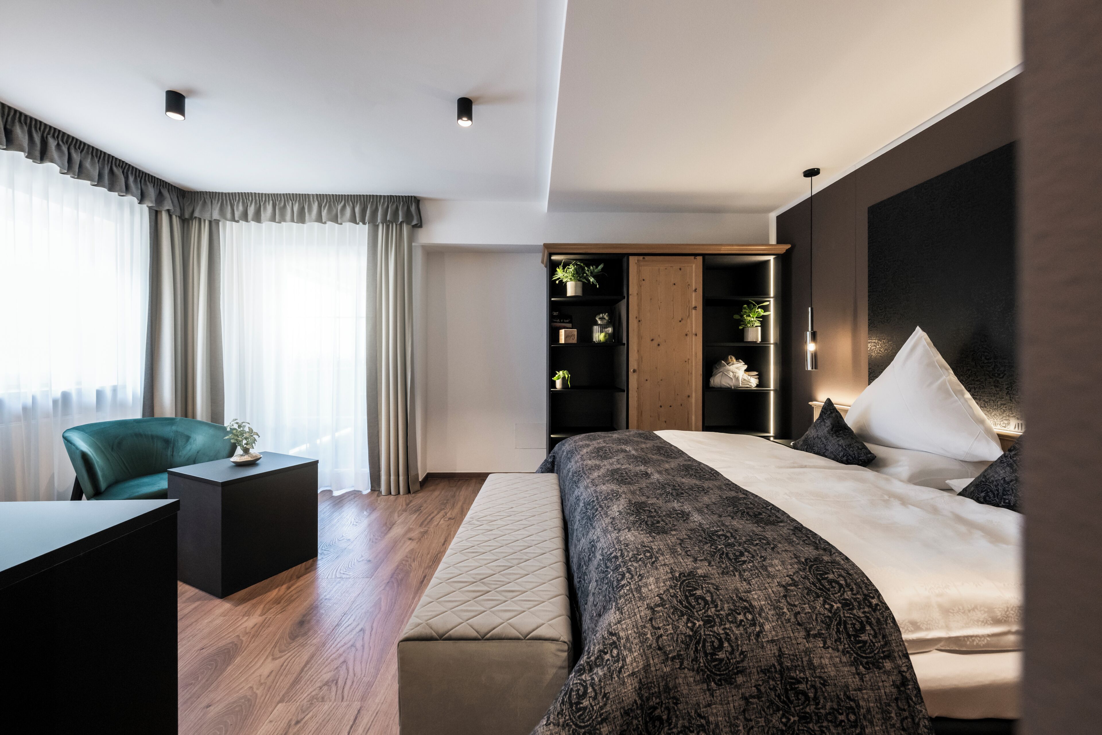 A modern bedroom with a bed, bedside tables, a desk, and a wardrobe.