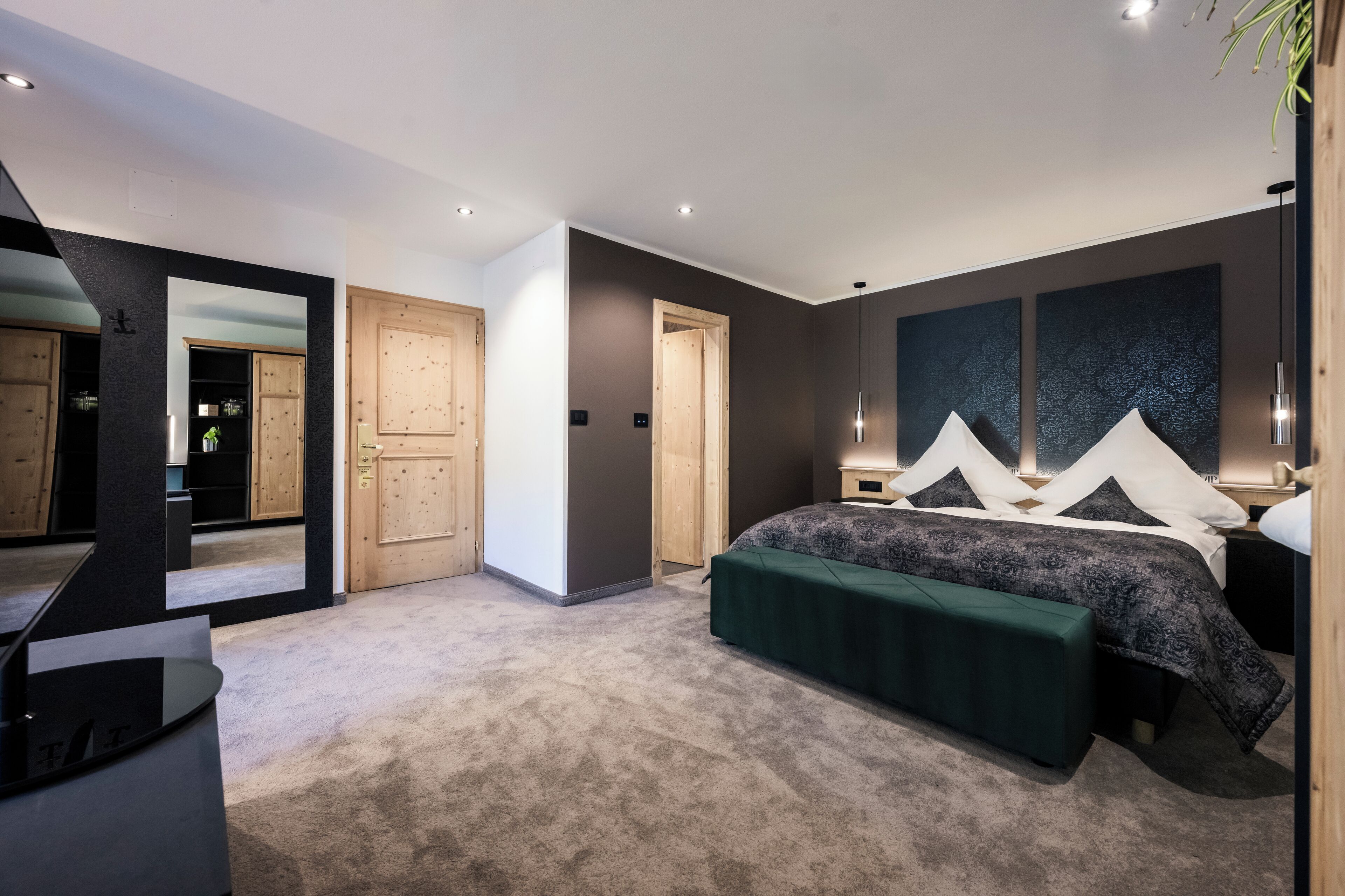 Un dormitorio moderno con una cama grande, un banco verde y un espejo que refleja la habitación.