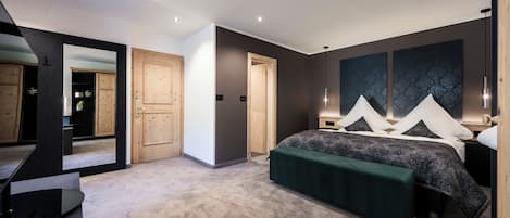 A modern bedroom with a large bed, a green bench, and a mirror reflecting the room.
