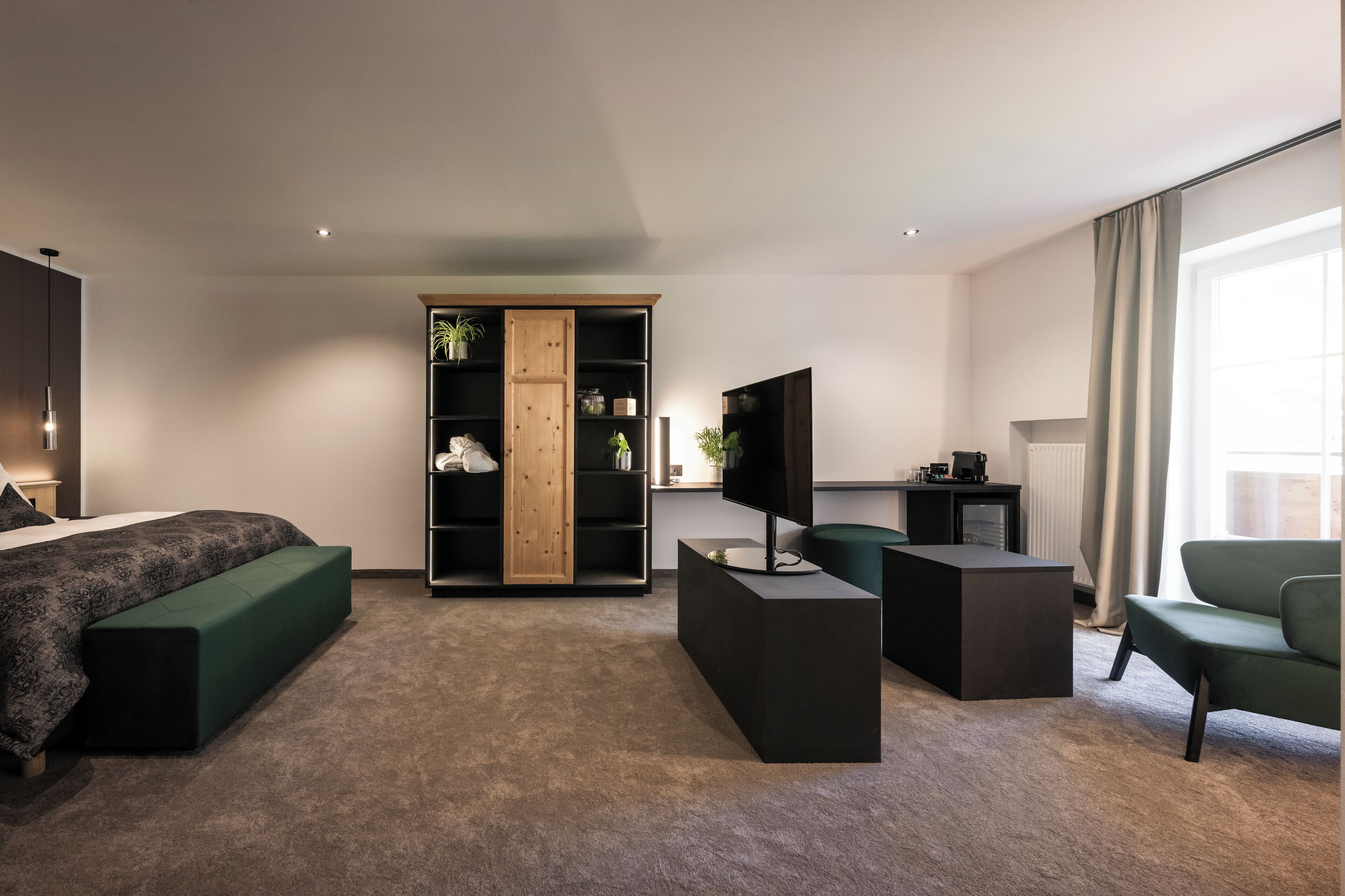 A modern bedroom with a bed, a green sofa, a TV, a wooden cabinet, and a desk.
