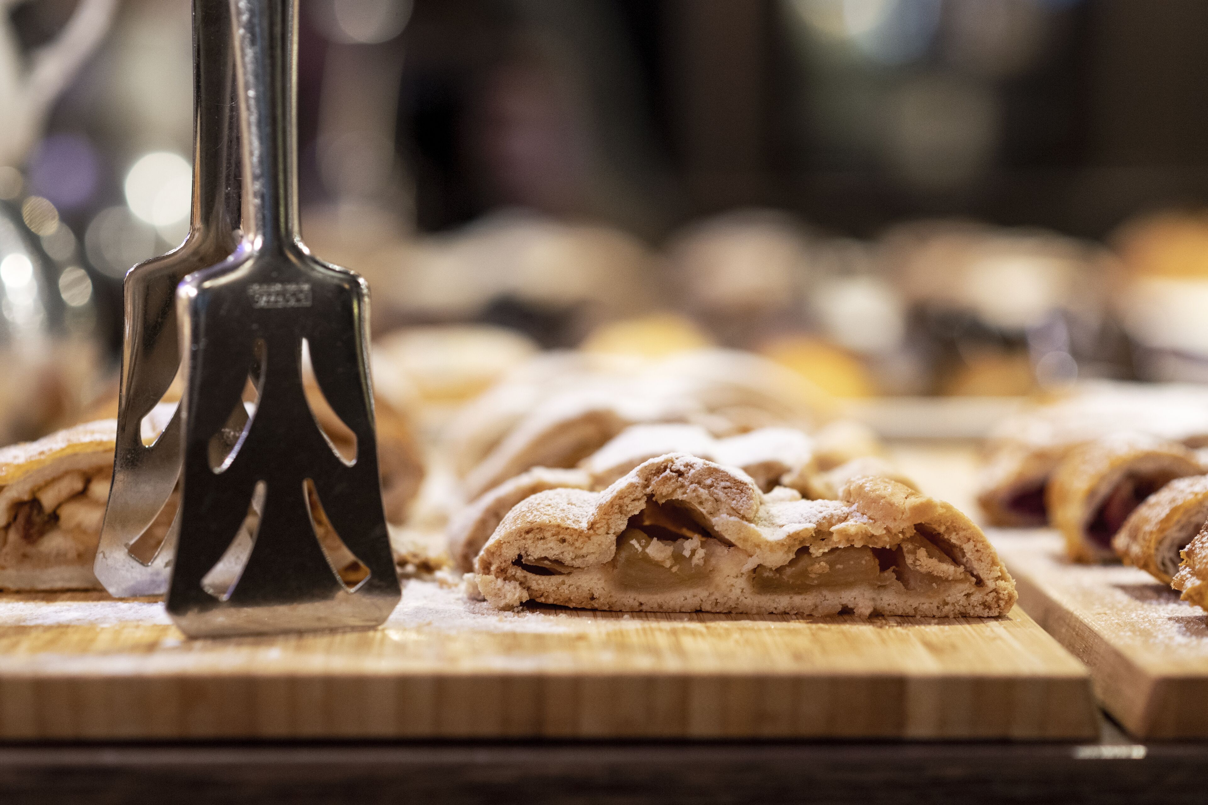 A wooden cutting board with sliced pastries and a metal pastry cutter.