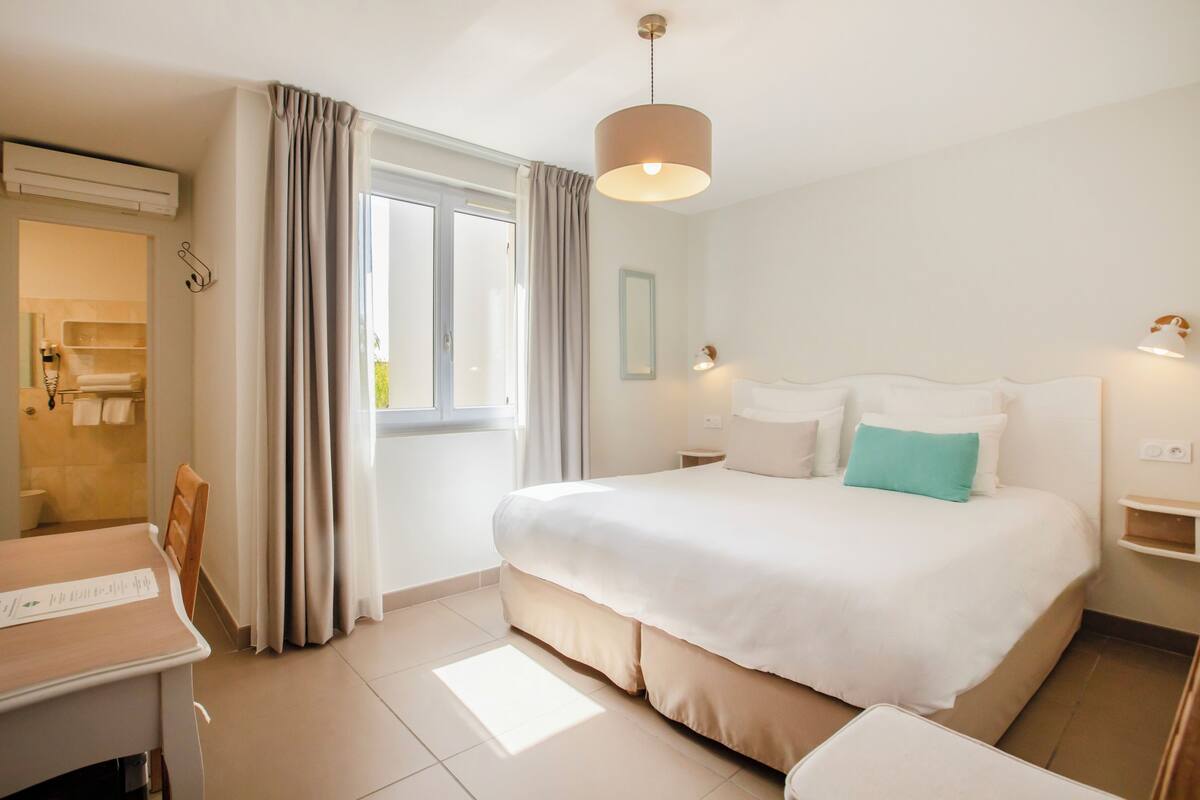 Une chambre d’hôtel avec un lit, une table de chevet, une lampe et une vue sur la salle de bain.