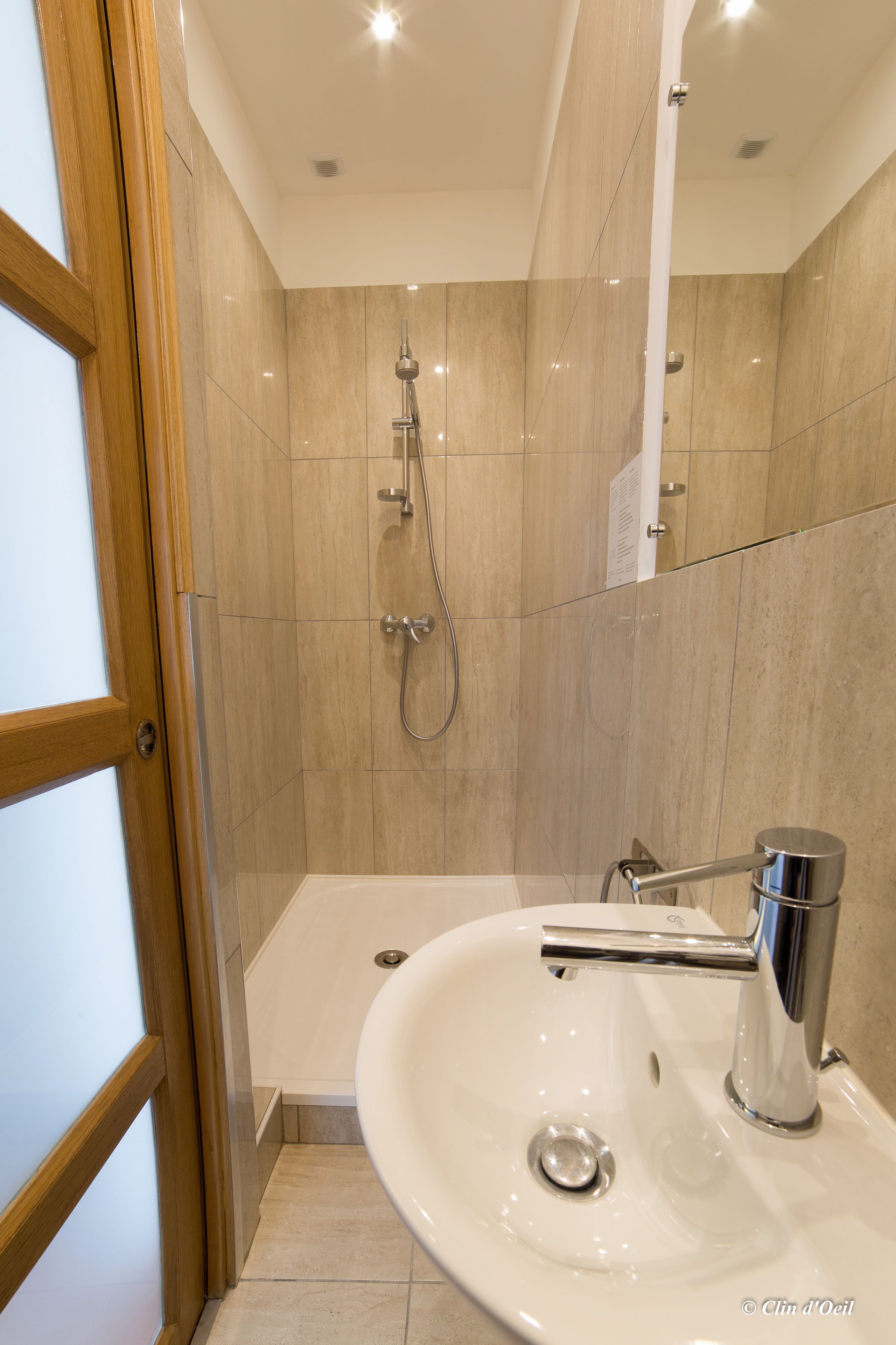 A bathroom with a shower, a sink, and a mirror.