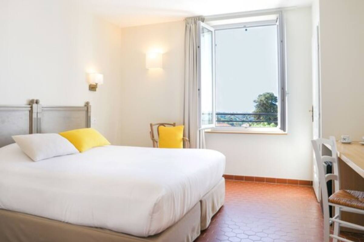 Une chambre d’hôtel avec un lit, une chaise, une fenêtre et une vue sur l’extérieur.
